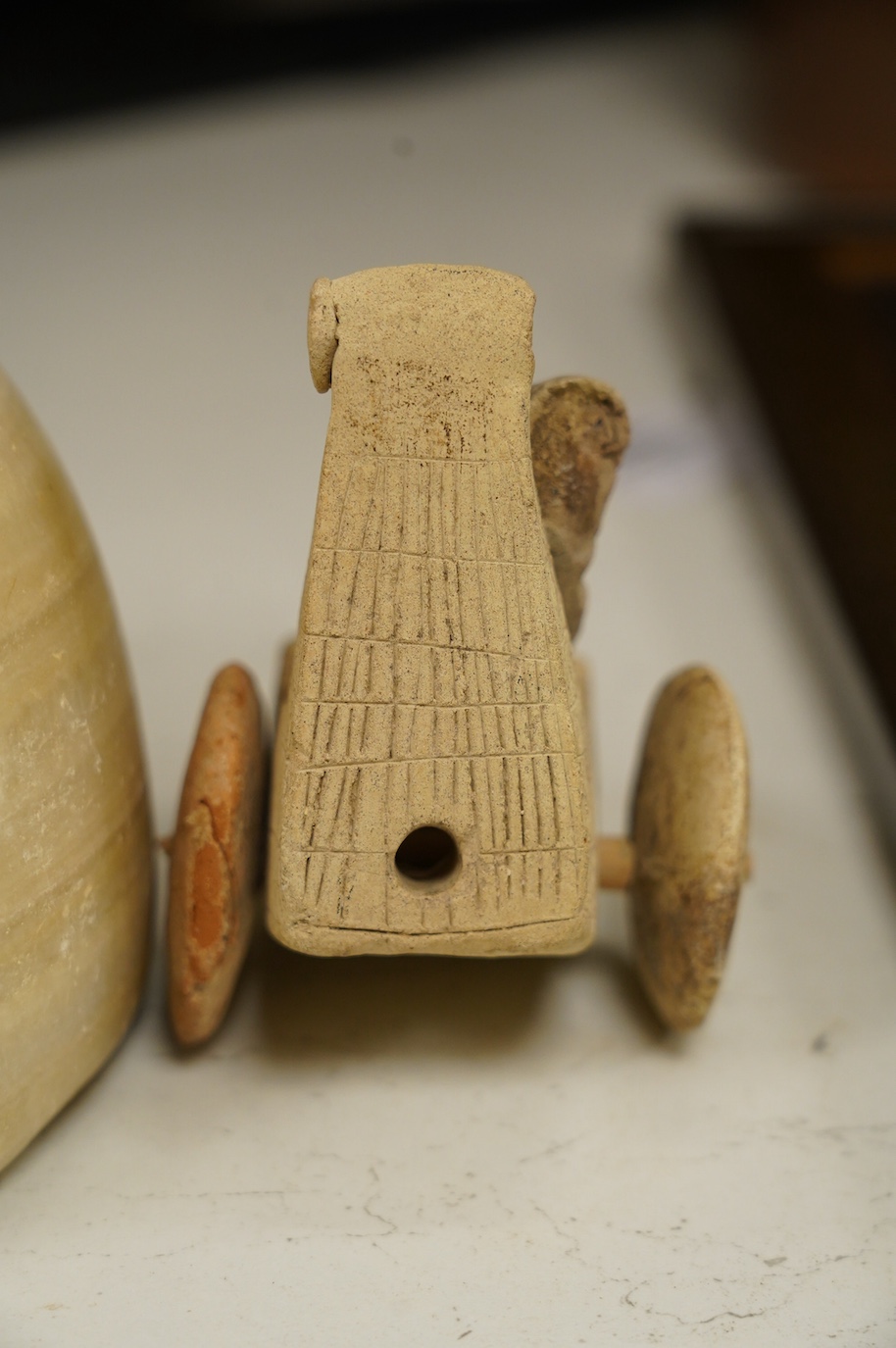 An alabaster mortar, possibly Ancient Egyptian, 17cm diameter, the handles ground off and a terracotta figure with chariot, possibly Mesopotamian. Condition - fair, restoration to chariot